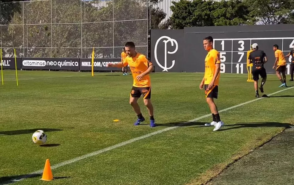 Ramiro, meia do Corinthians, participa de treinamento enquanto é observado pelo companheiro Mateus Vital.